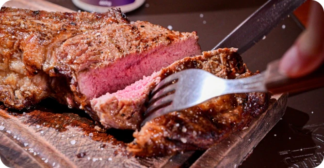 Prato de costela assada no estilo prime rib servida em uma tábua de madeira com acompanhamentos.