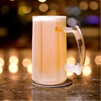 Caneca de chopp trincando de gelada com espuma, servida no balcão do bar do Steak Ranch.